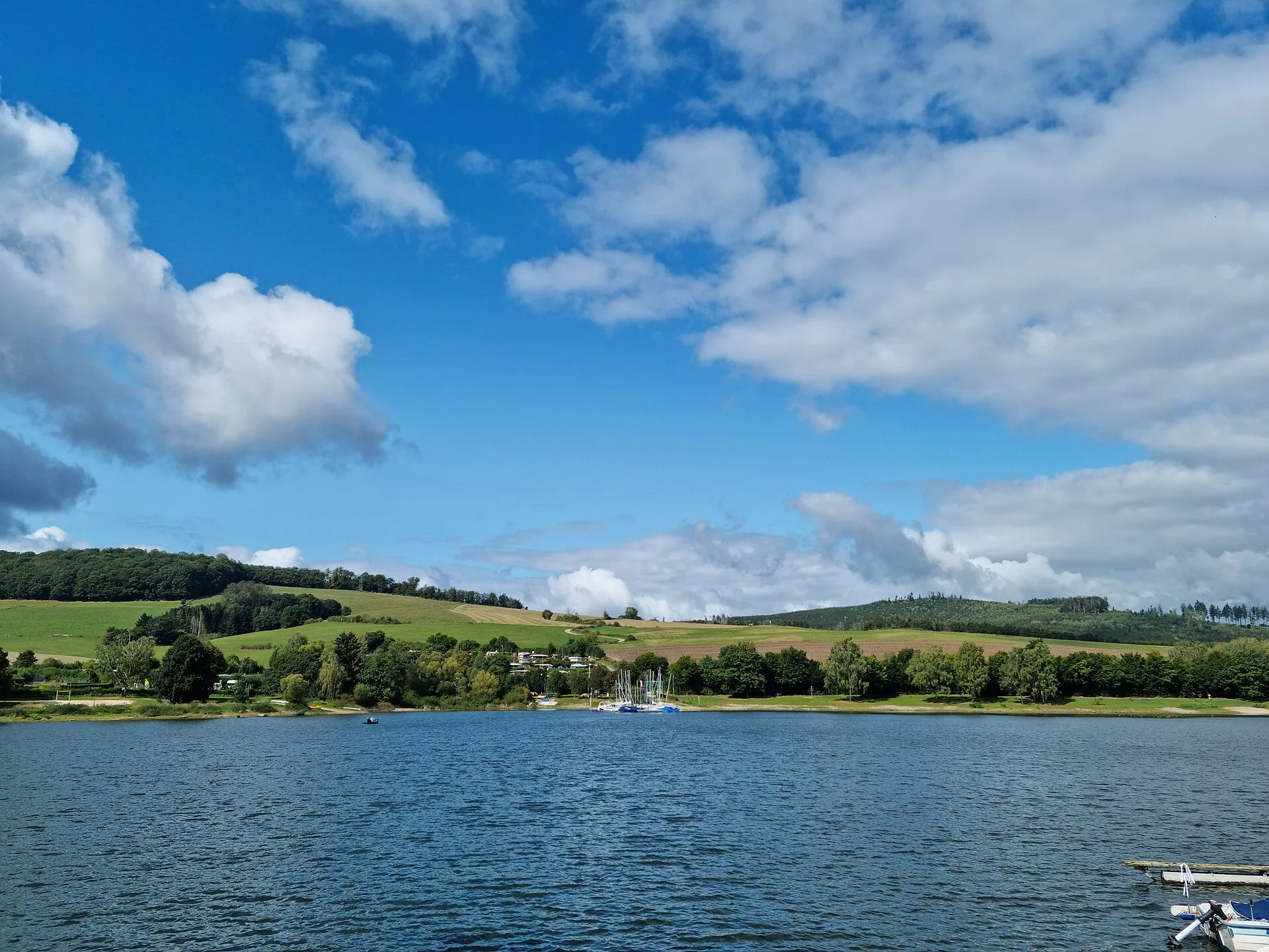 Diemelsee met aangemeerde zeilboten en beboste heuvels onder een blauwe lucht in het Sauerland