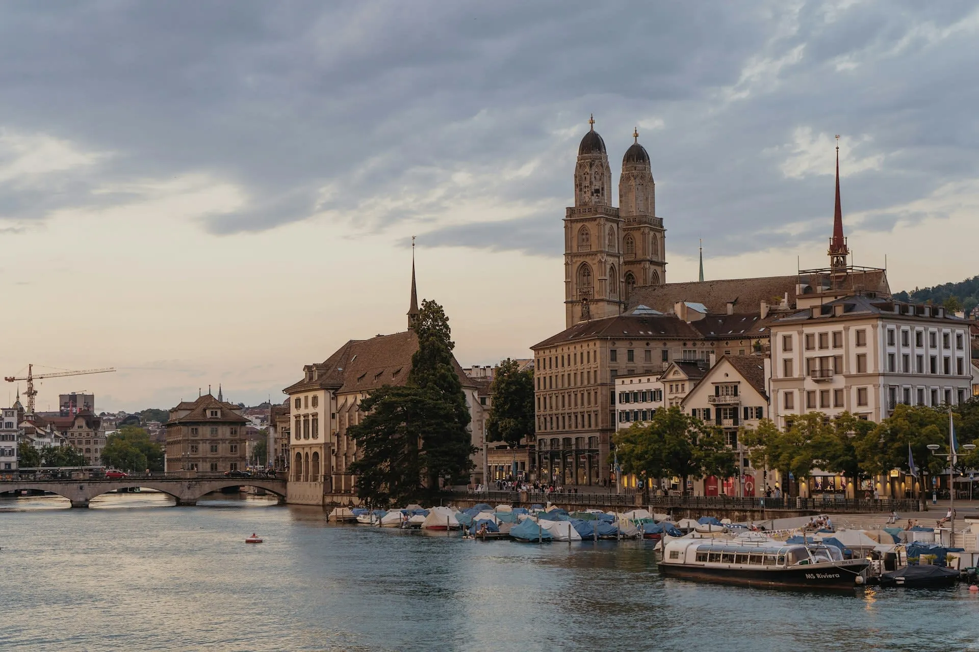 Grossmünster en de Limmat in Zürich bij avondlicht met aangemeerde boten