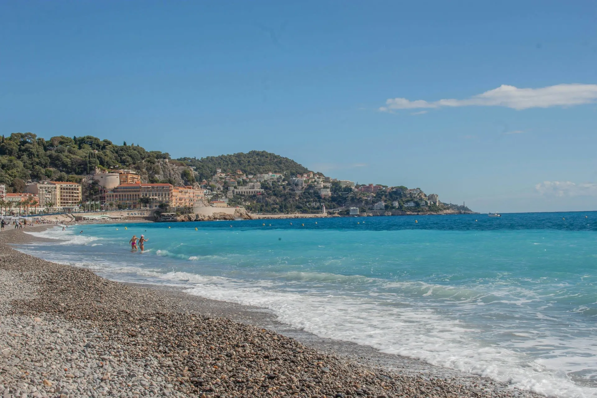 Kiezelstrand van Nice met turquoise zee en de heuvels van de oude stad