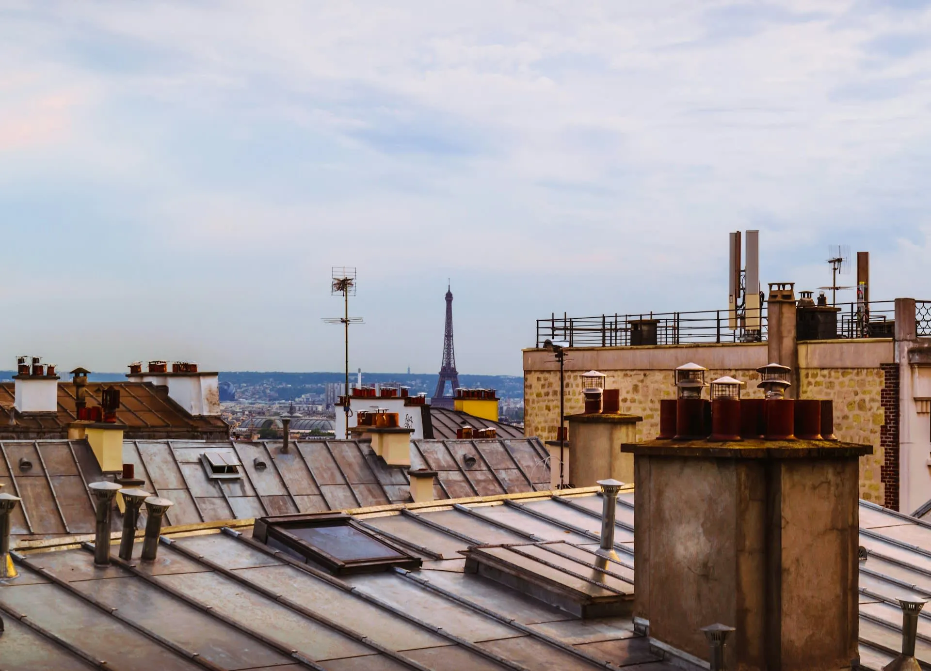 Parijse daken bij Montmartre met de Eiffeltoren in de verte in avondlicht