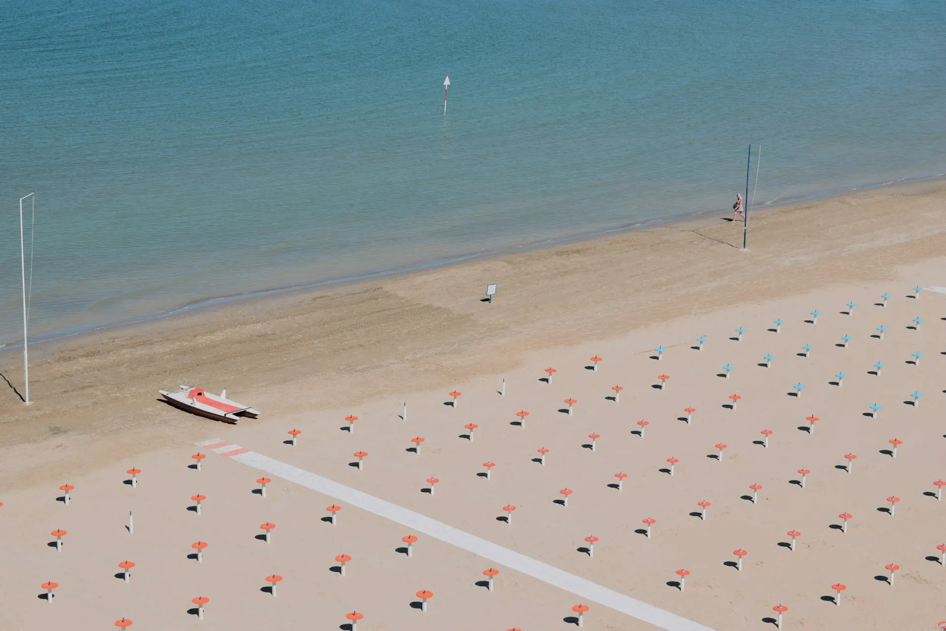 Strand van Rimini met rijen oranje parasols en de turquoise Adriatische Zee vanuit vogelperspectief
