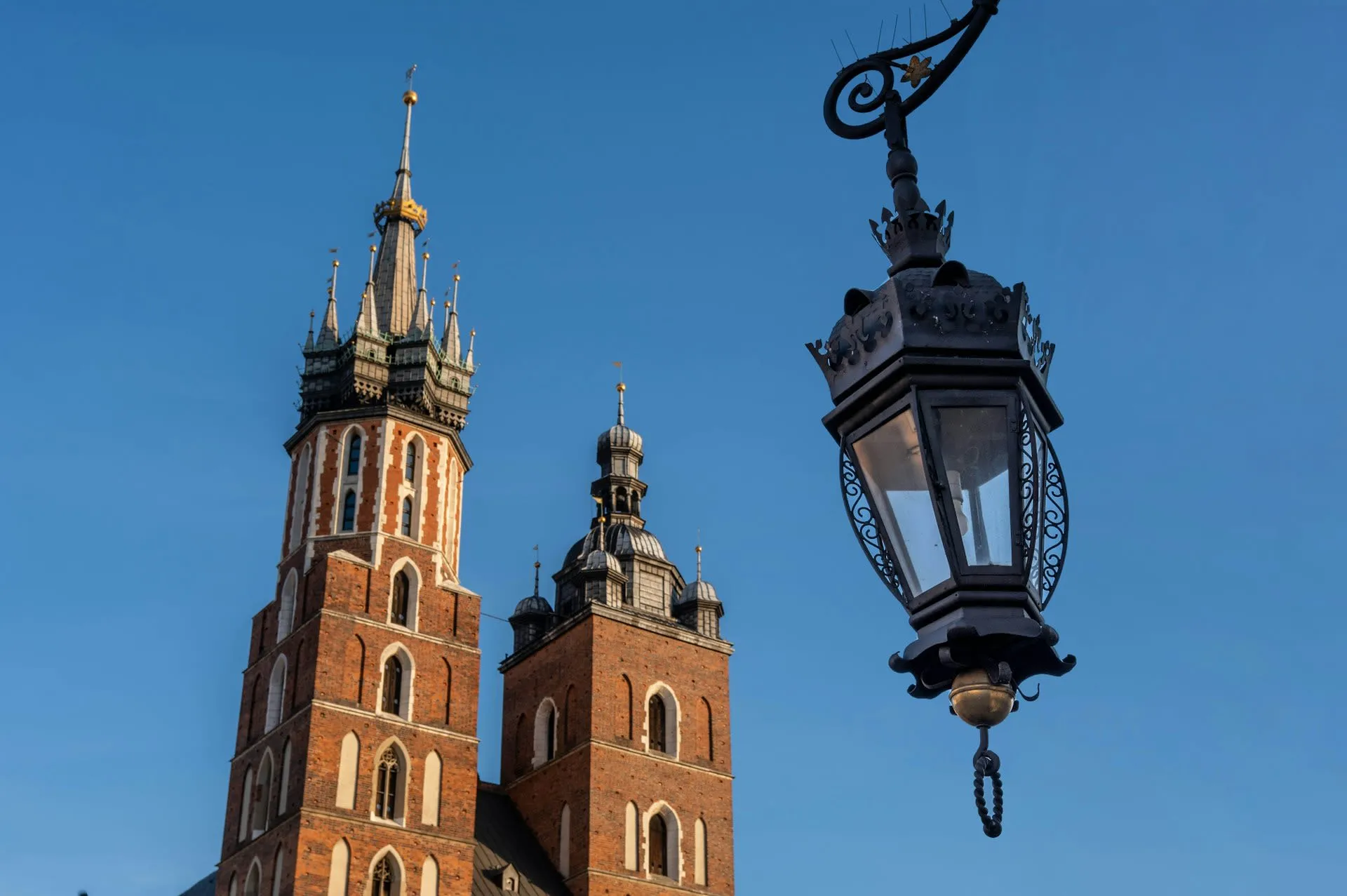 Torens van de Mariakerk in Krakau naast een sierlijke smeedijzeren straatlantaarn