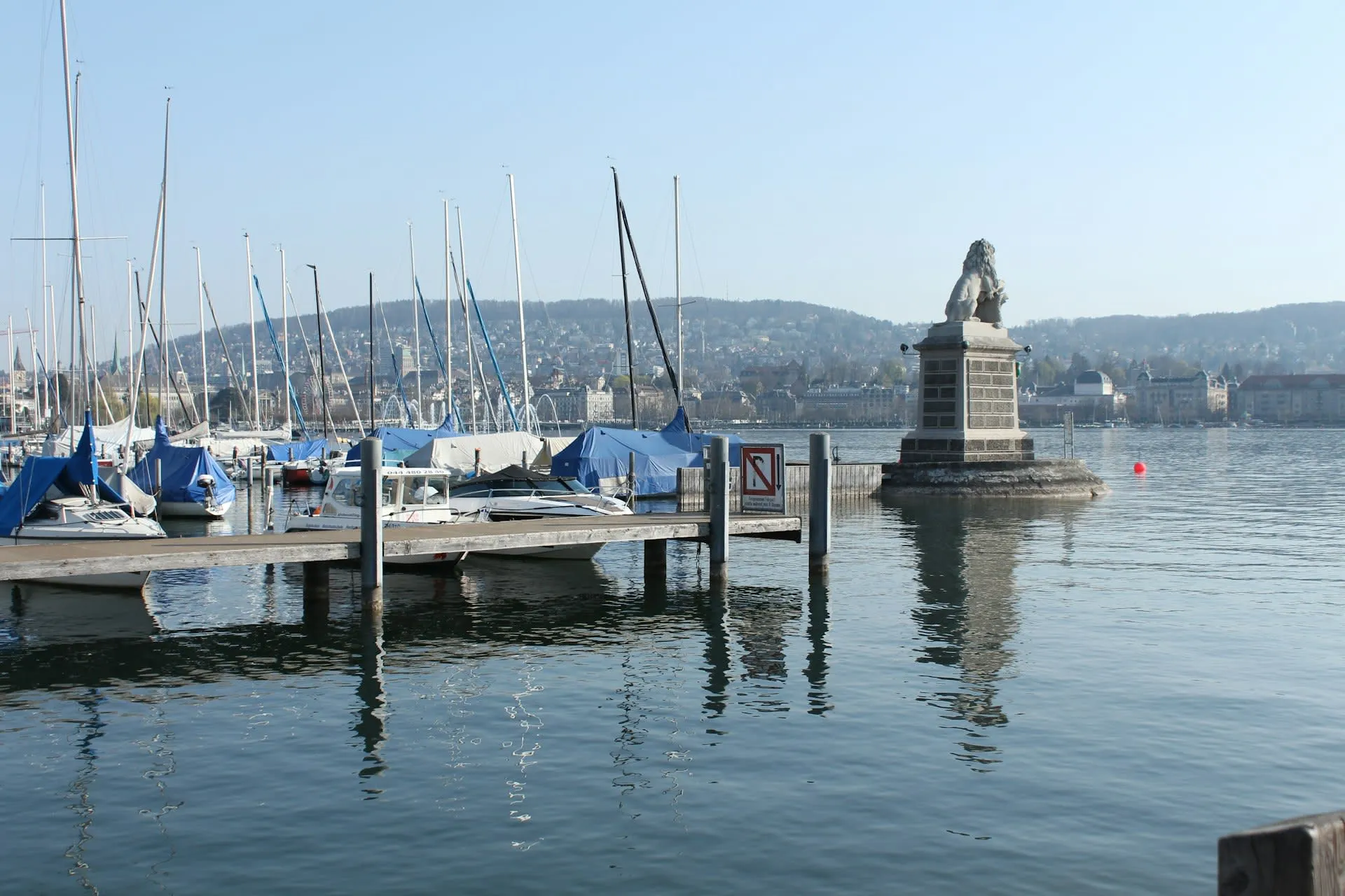 Jachthaven aan de Zürichsee met leeuwenbeeld en de stad Zürich op de achtergrond