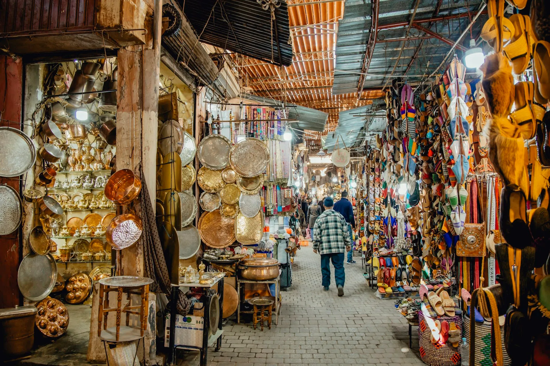 Overdekte souk in Marrakech met glanzend koperwerk, tajines en kleurrijke slippers